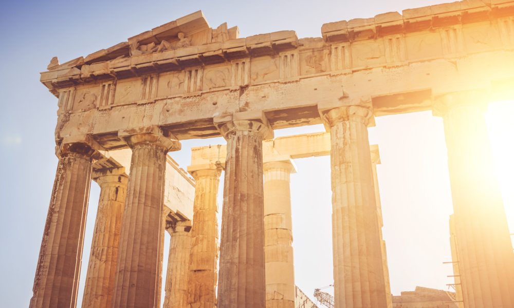 The Parthenon temple in Athens, over the acropolis of the ancient Greek city. The photo was taken during an hot summer day, with sun behind the marble columns of the ancient temple.